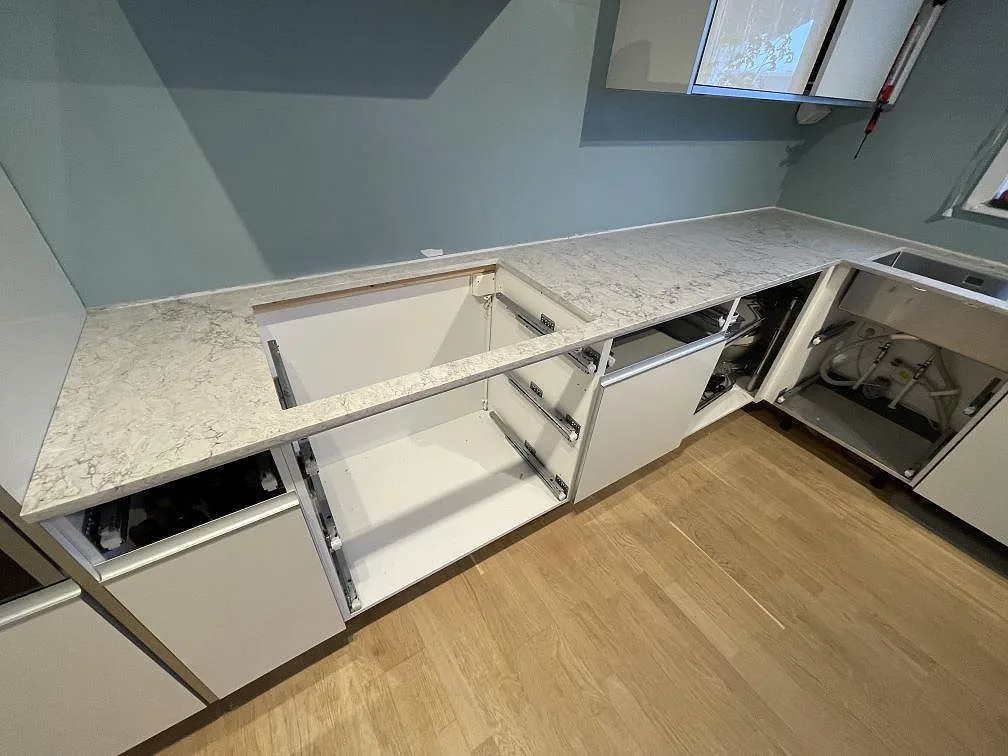 L-formad köksbänk i Caesarstone Moorland Fog, polerad kvartskomposit, under montering i ett kök i Huddinge.