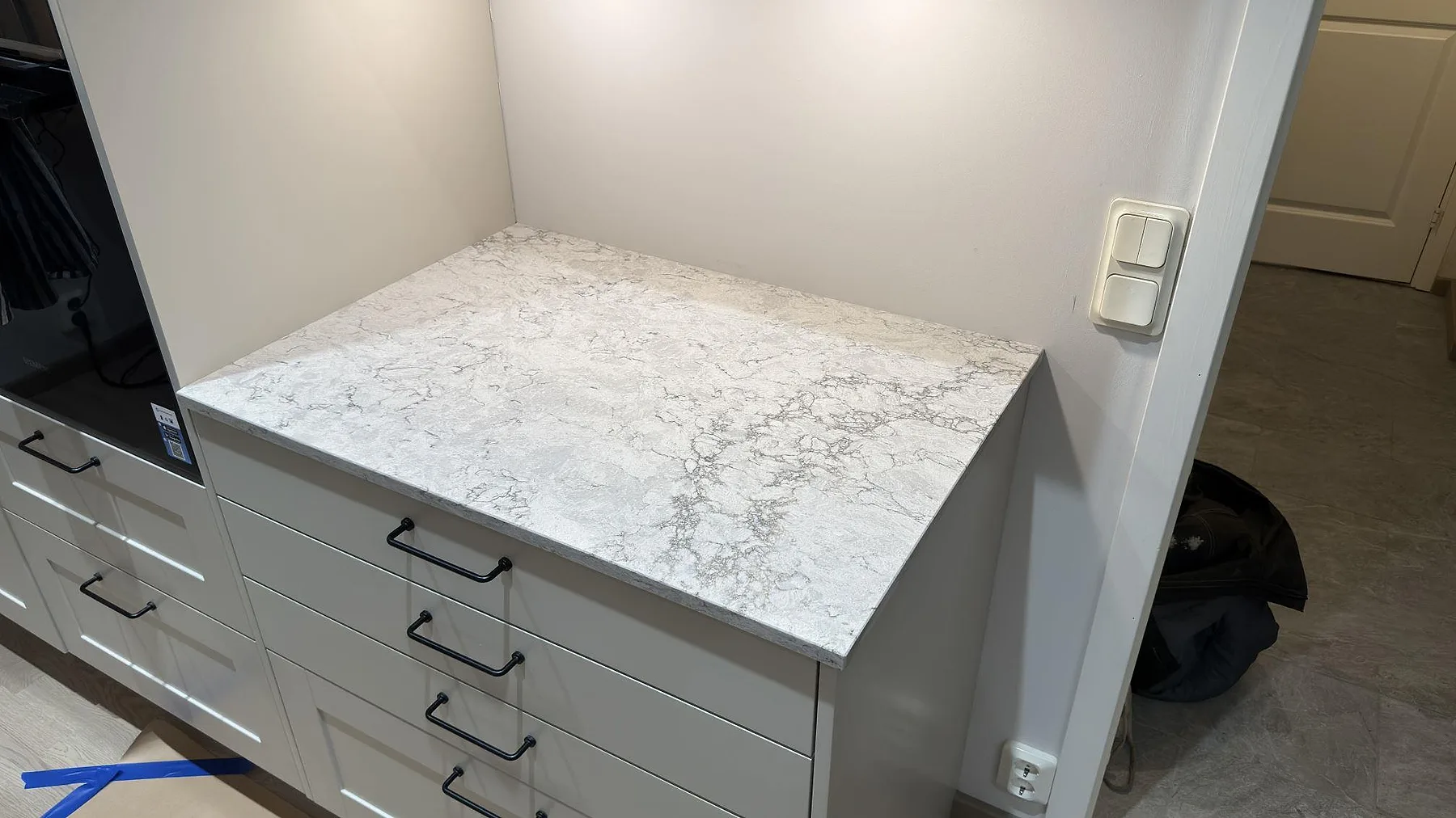 Polerad bänkskiva i Caesarstone Moorland Fog ovanpå grå köksskåp i ett kök i Knivsta, med tydlig grå ådring i det ljusa kompositet.