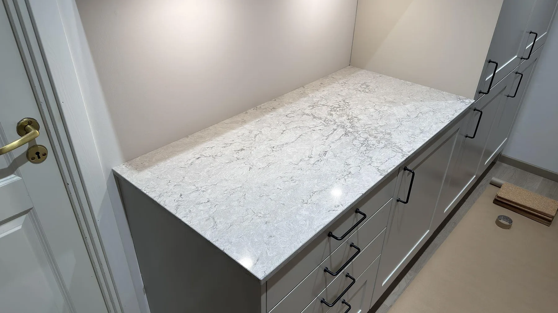 Bänkskiva i Caesarstone Moorland Fog på grå lådhurts längs väggen, polerad grå komposit med mjuk ådring, i ett kök i Knivsta.