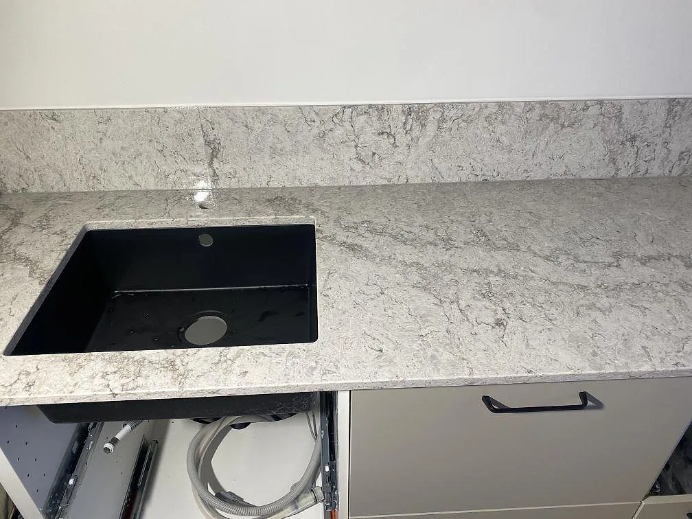 Närbild på den svarta underlimmade komposithoaren och den ådrade ytan i Caesarstone Moorland Fog, i ett kök i Limhamn.