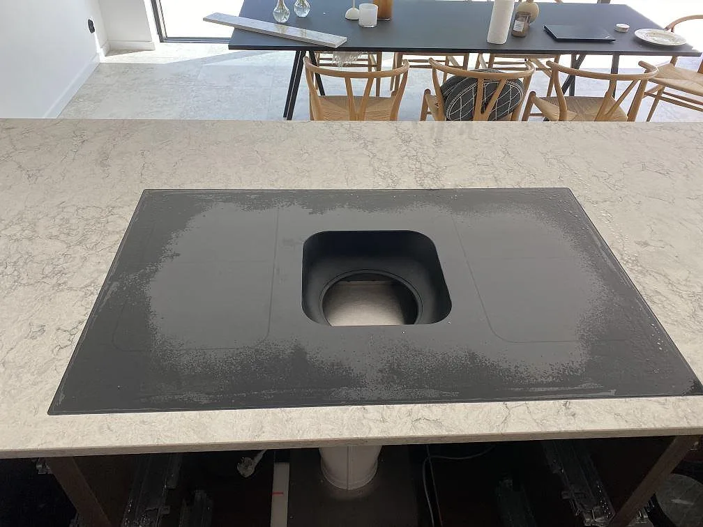 Detalj av polerad köksbänkskiva i Caesarstone Moorland Fog med svart häll och grå ådring i Lomma.