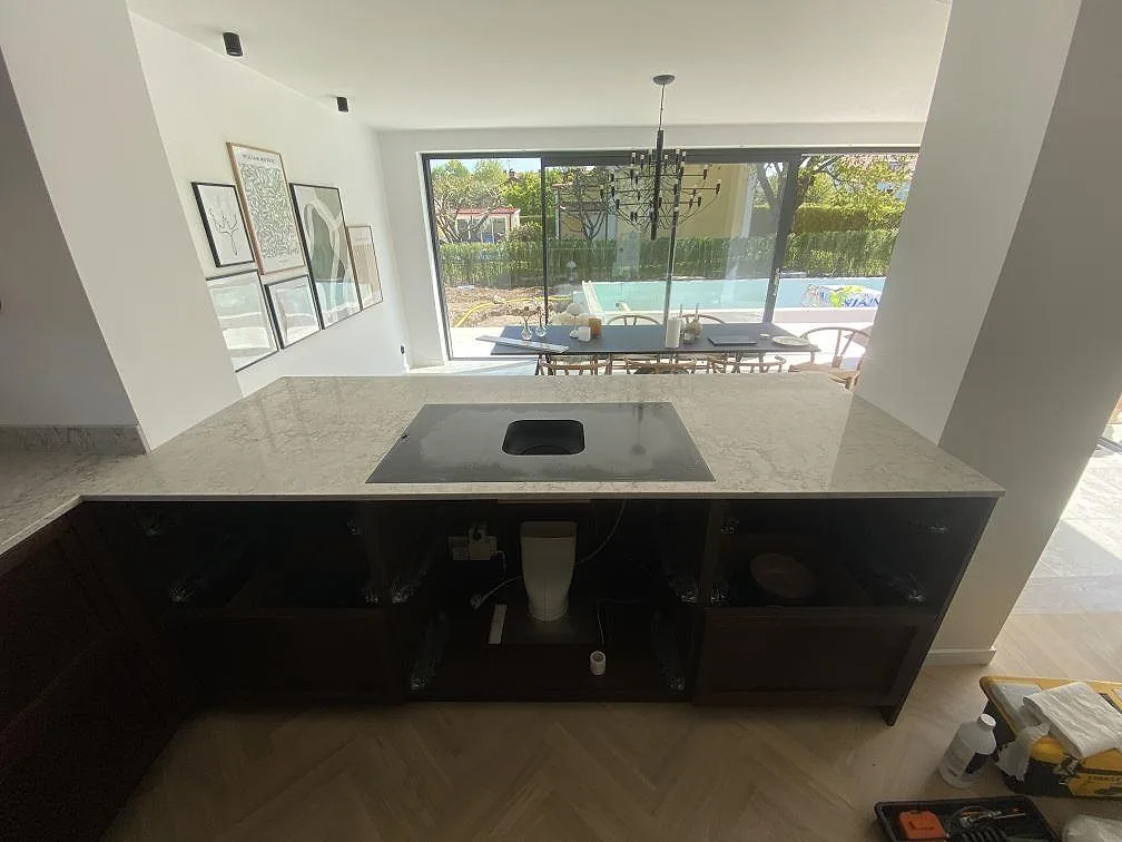 Köksö med köksbänkskiva i Caesarstone Moorland Fog, polerad komposit, över mörka stommar i ett kök i Lomma.