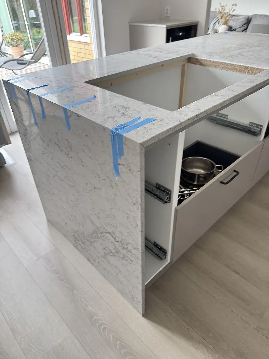 Köksö med bänkskiva och nedvikt stensida i Caesarstone Moorland Fog, polerad ljusgrå kvartskomposit, i ett kök i Lund.