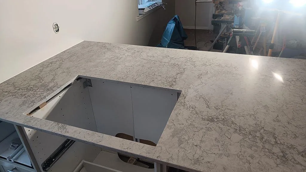 Detalj av hälluttag i polerad Caesarstone Moorland Fog på köksö under montering i Malmö.