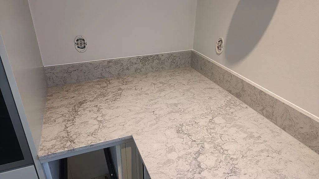 Bänkskiva i Caesarstone Moorland Fog med uppvikt stänkkant och polerad yta vid vägg i Malmö.