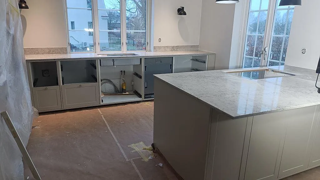 Köksbänkskiva i Caesarstone Moorland Fog, polerad, med stor köksö och bänkar vid fönster i ett kök i Malmö.