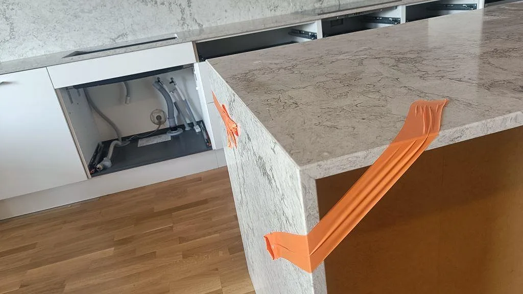 Sidovy av köksö i polerad Caesarstone Moorland Fog med stenfront, ljus ådring och monteringsband i Malmö.