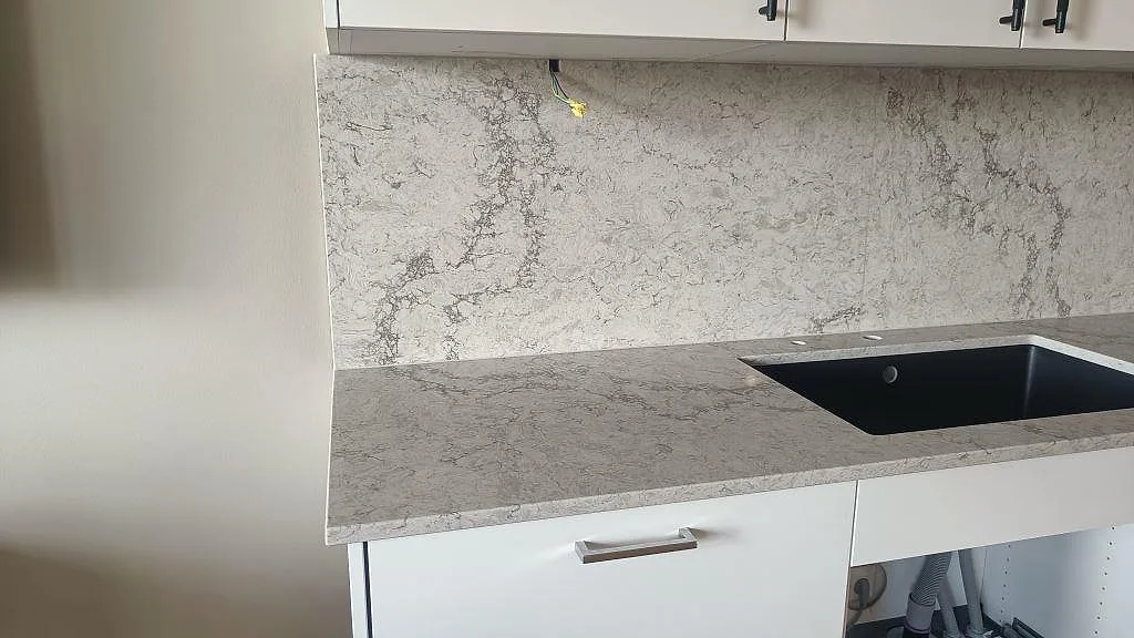 Köksbänkskiva i polerad Caesarstone Moorland Fog med svart underlimmad diskho och högt stänkskydd i Malmö.
