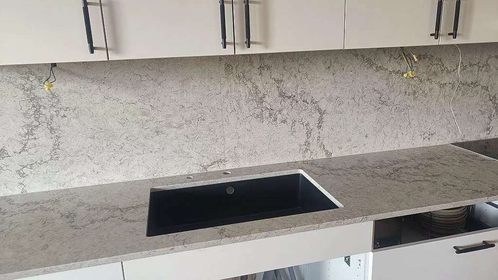 Bänkskiva i polerad Caesarstone Moorland Fog med underlimmad svart diskho och stänkskydd i kök i Malmö.