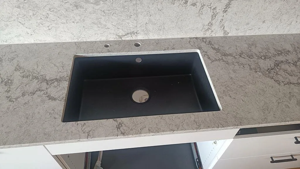 Detalj av underlimmad diskho i polerad Caesarstone Moorland Fog med borrhål för blandare i Malmö.