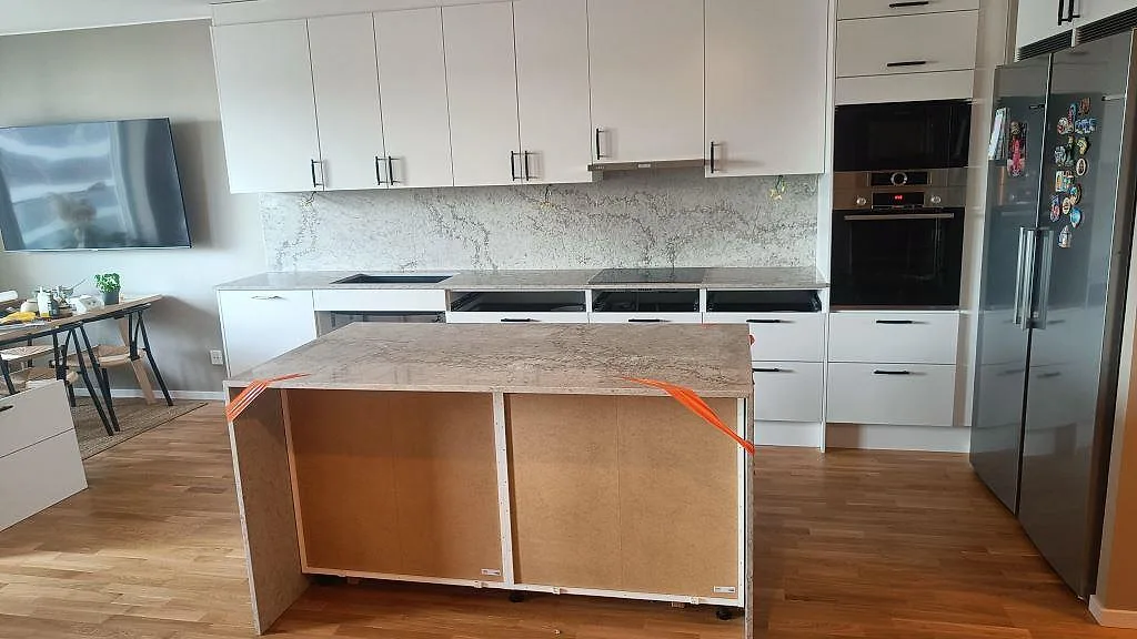 Köksbänkskiva och köksö i polerad Caesarstone Moorland Fog med stänkskydd, underlimmad diskho och häll i ett kök i Malmö.