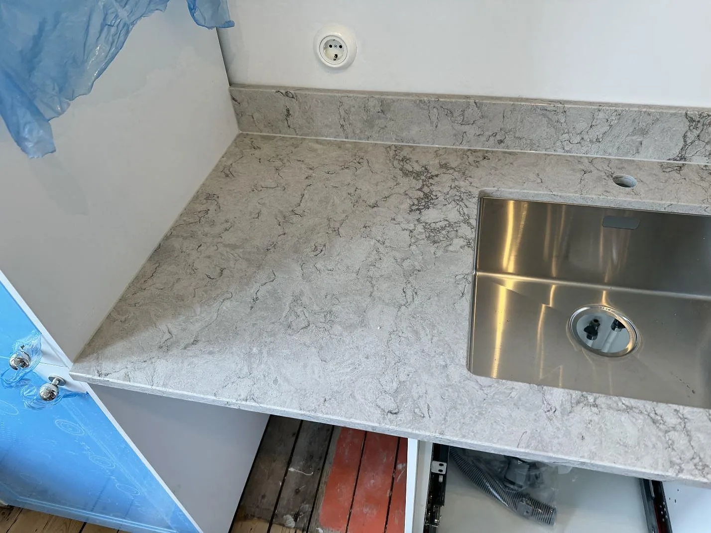 Detalj av polerad Caesarstone Moorland Fog som arbetsyta vid rostfri diskho och låg stänkkant i ett kök i Malmö.