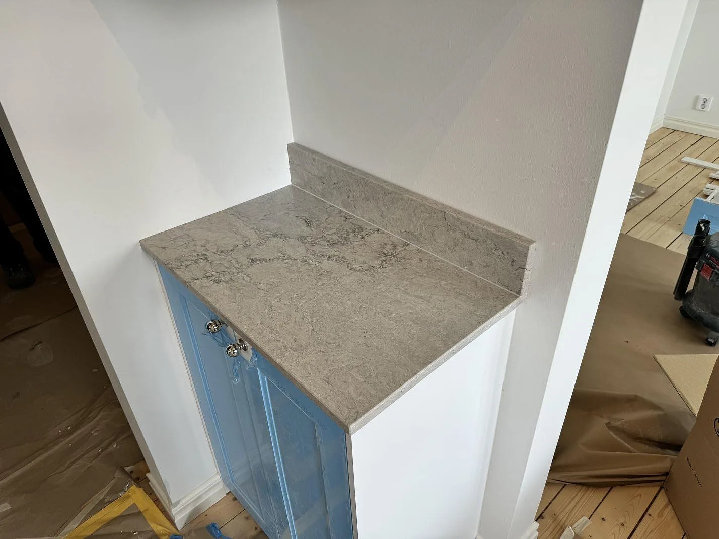 Kort sidobänk i Caesarstone Moorland Fog, polerad grå kvartskomposit med låg stänkkant, monterad i ett kök i Malmö.