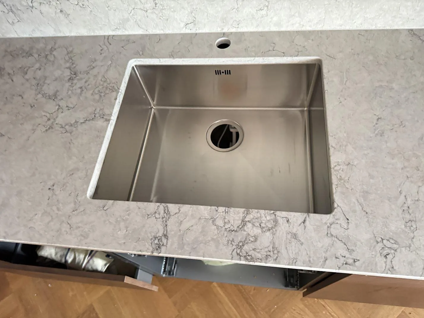 Ovanvy av underlimmad rostfri diskho i polerad Caesarstone Moorland Fog, ljus kvartskomposit med grå ådring i ett kök i Malmö.