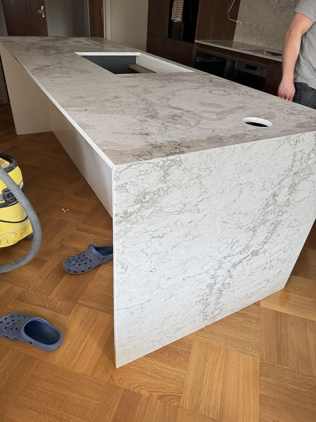 Stenklädd gavel och arbetsyta i polerad Caesarstone Moorland Fog med hällurtag och rund genomföring i ett kök i Malmö.