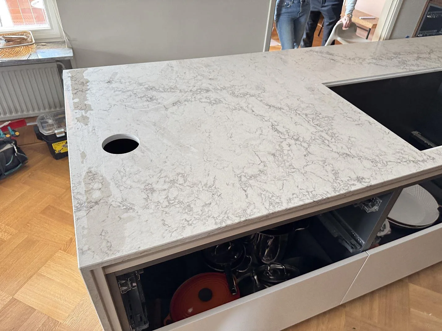 Separat arbetsyta i polerad Caesarstone Moorland Fog med förberett hällurtag och runt genomföringshål under montering i Malmö.