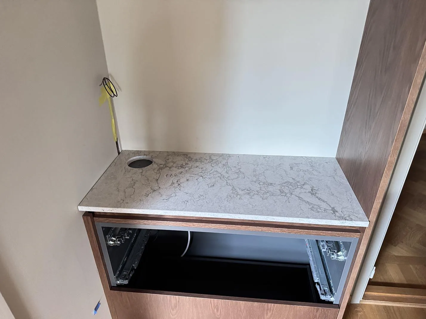 Mindre bänkyta i polerad Caesarstone Moorland Fog med runt urtag och öppna köksstommar under montering i Malmö.