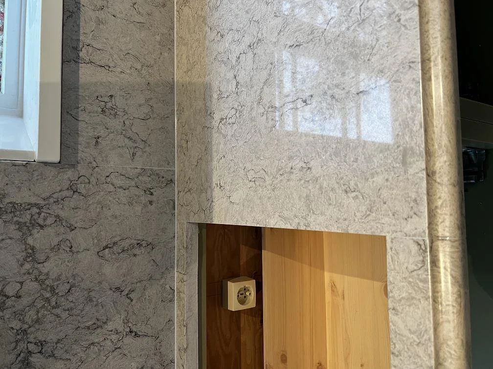Detalj av stänkskydd i grå Caesarstone Moorland Fog mot fönster i ett kök i Moheda.