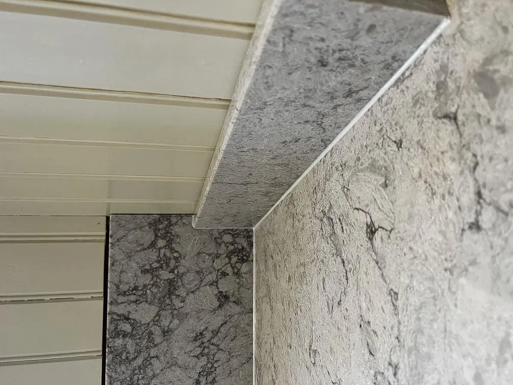 Närbild på uppvikt stänkkant i polerad Caesarstone Moorland Fog med fin ådring i ett kök i Moheda.