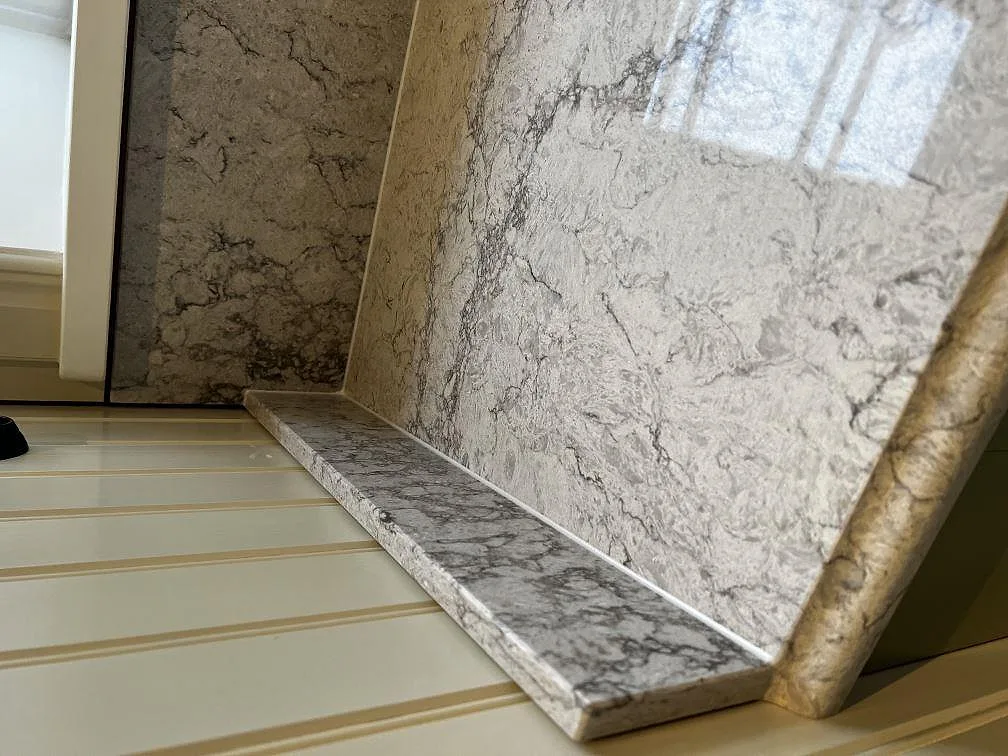 Stenfönsterbänk och stänkskydd i polerad Caesarstone Moorland Fog vid ett fönster i ett kök i Moheda.