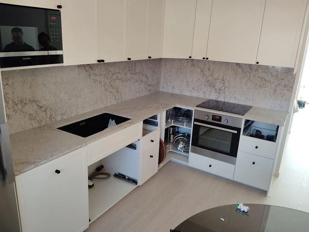 Köksbänkskiva i polerad Caesarstone Moorland Fog, 20 mm, med urtag för diskho och häll i ett U-format kök i Norsborg.