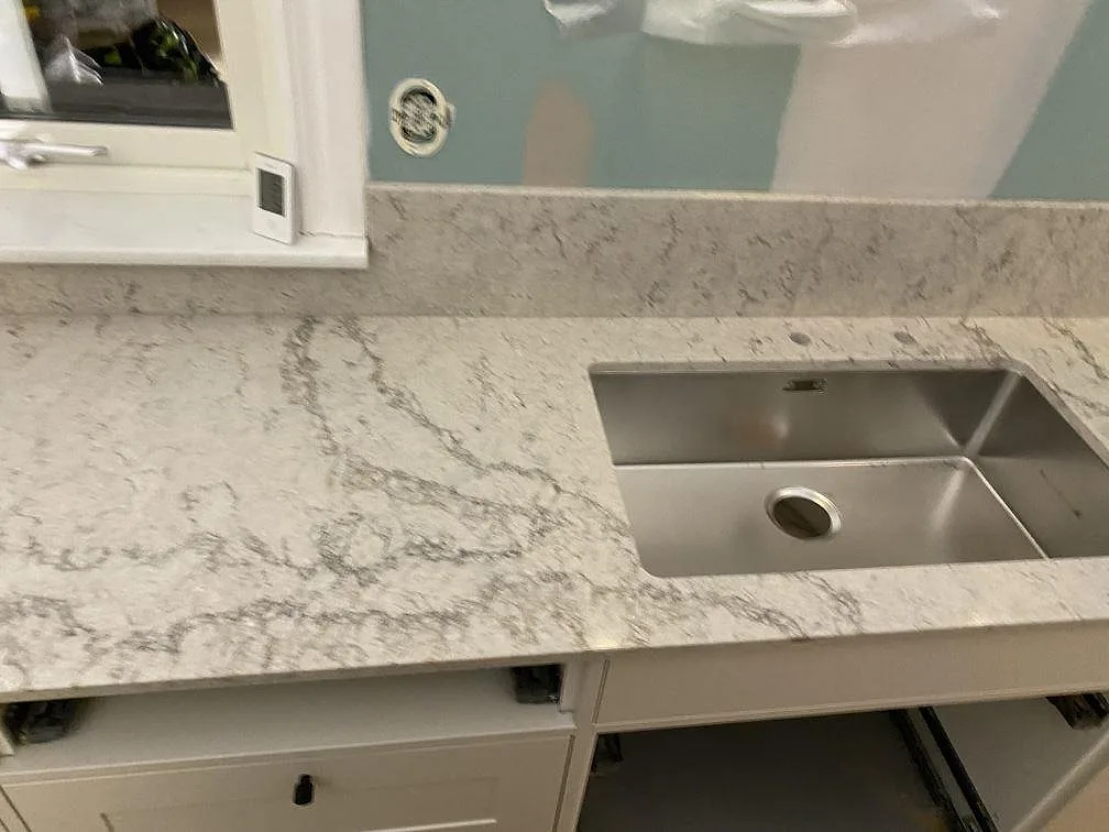 Rostfri diskho monterad under köksbänkskiva i Caesarstone Moorland Fog med matchande stänkkant i ett kök i Sandared.
