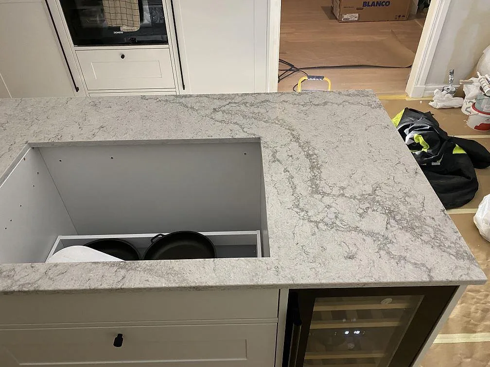 Underlimmad diskho i rostfritt stål i polerad bänkskiva i Caesarstone Moorland Fog med två kranhål i ett kök i Sandared.