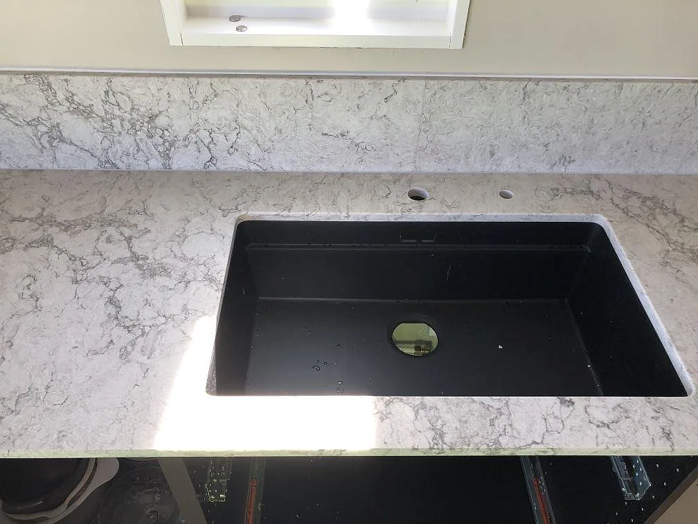 Köksbänkskiva i Caesarstone Moorland Fog med svart underlimmad kompositdiskho och kranhål i ett kök i Skegrie.