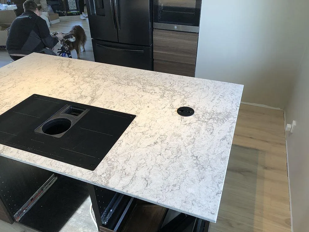 Köksö i Caesarstone Moorland Fog med urtag för induktionshäll, sedd ovanifrån under montering i ett kök i Skegrie.