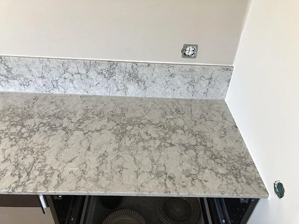 Hörn av köksbänkskiva i Caesarstone Moorland Fog med uppvikt stänkkant och matt yta i ett kök i Skegrie.