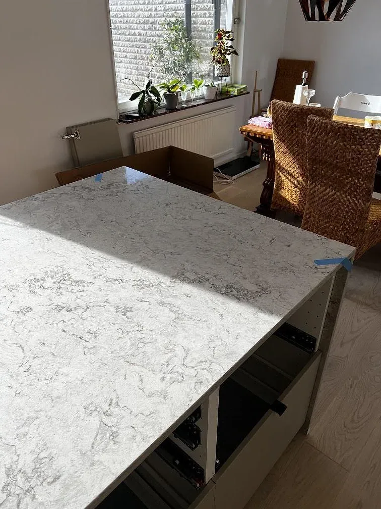 Köksö i Caesarstone Moorland Fog med ljus polerad yta och grå ådring, fotograferad vid fönster och träinredning i Skurup.