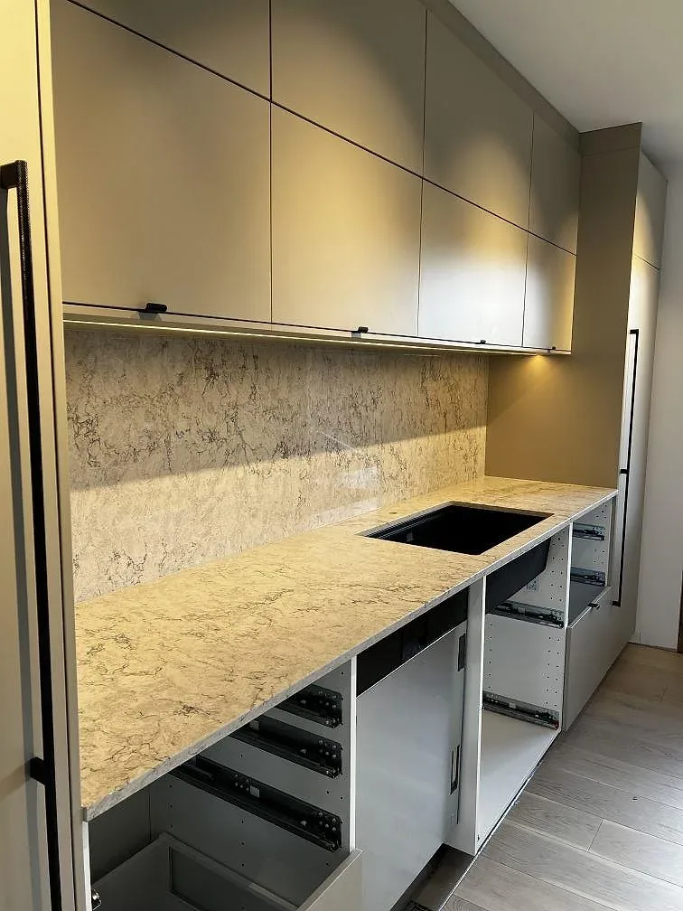 Väggbänk och uppvikt stänkskydd i Caesarstone Moorland Fog, polerad komposit, med svart underlimmad diskho i Skurup.