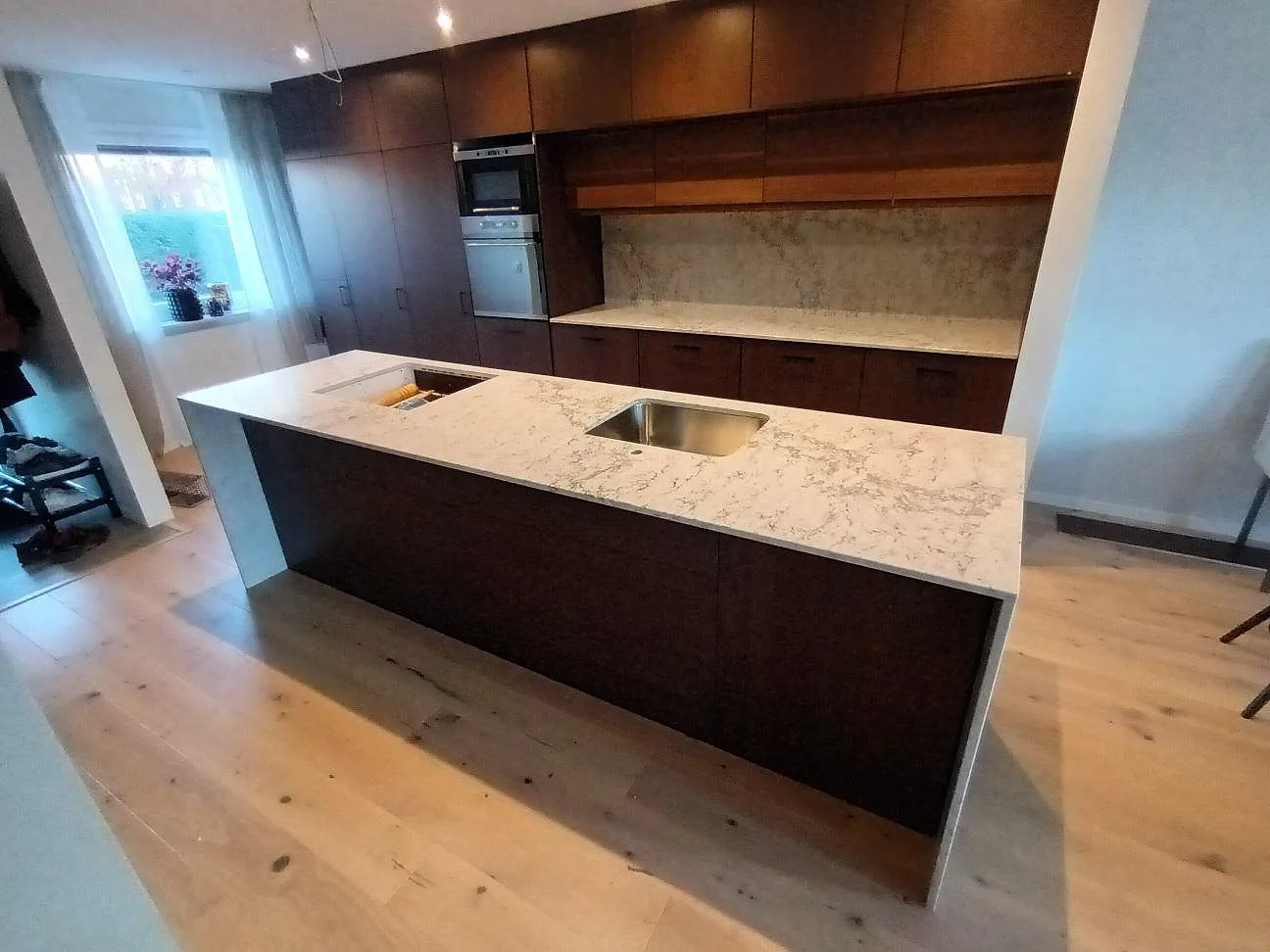 Köksbänkskiva i Caesarstone Moorland Fog, polerad komposit, med rostfri diskho och hällöppning i en köksö i Sollentuna.