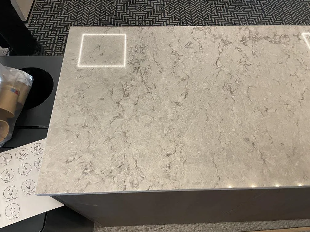Närbild på bänkskiva i Caesarstone Moorland Fog, polerad komposit med grå ådring och ett urtag i toppskivan, i ett kontor i Solna.