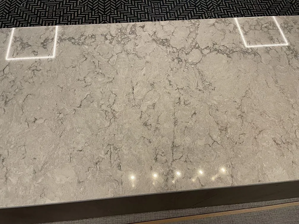 Toppskiva i Caesarstone Moorland Fog, ljusgrå polerad kvartskomposit med diskret ådring, i en kontorsmiljö i Solna.