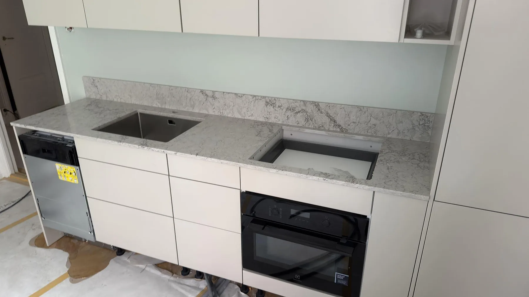 Polerad köksbänkskiva i Caesarstone Moorland Fog med rostfri diskho, förberett hällurtag och uppvikt stänkkant under montering i Stockholm.