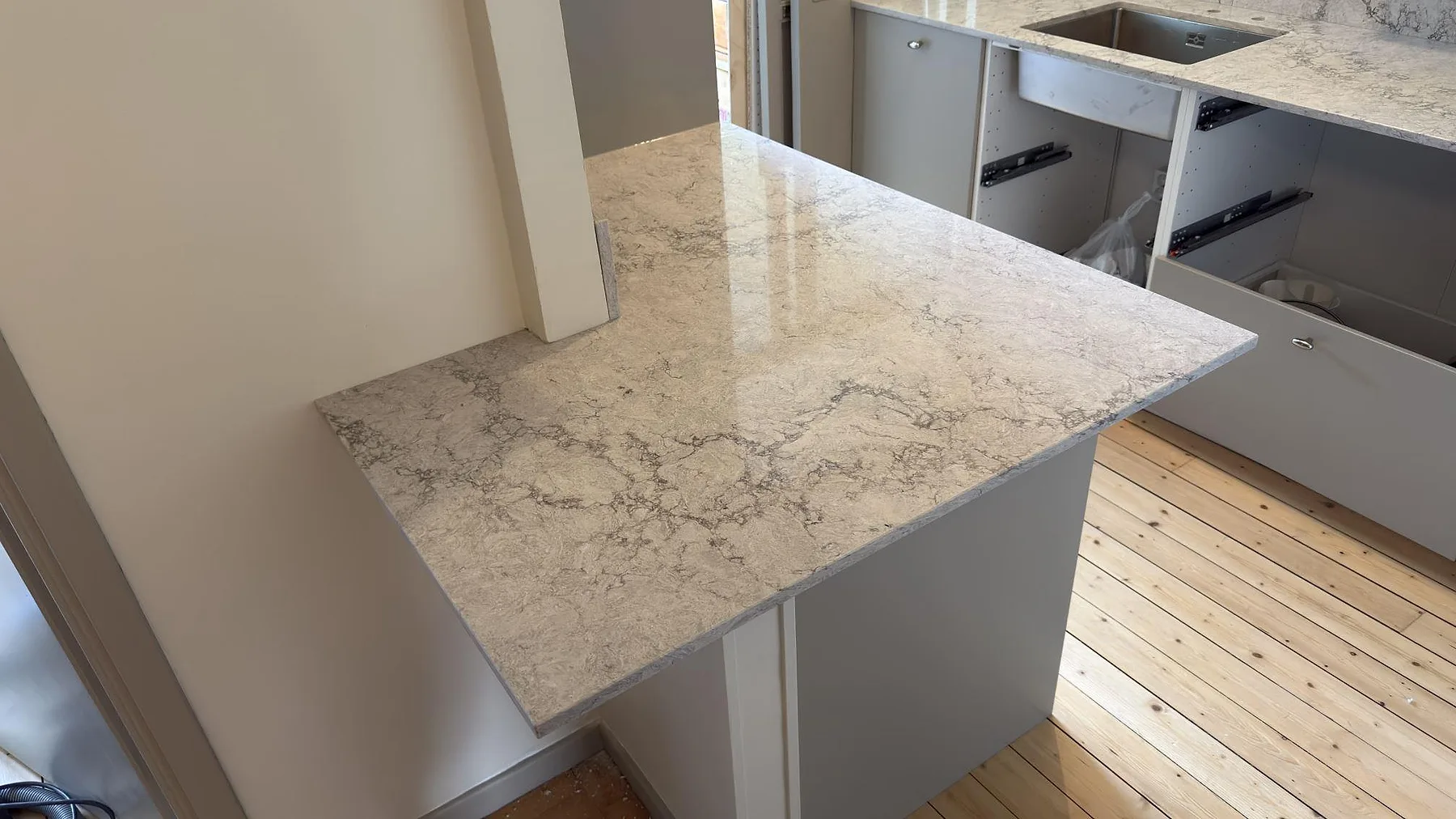Köksö med bänkskiva i Caesarstone Moorland Fog, ljusgrå kvartskomposit med diskret ådring, polerad, i ett kök i Stockholm.