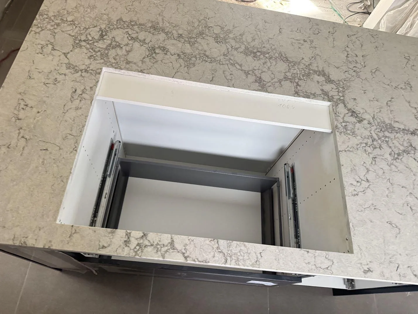 Närbild av hällurtag i köksö av polerad Caesarstone Moorland Fog, ljus kvartskomposit med grå ådring, i Svedala.