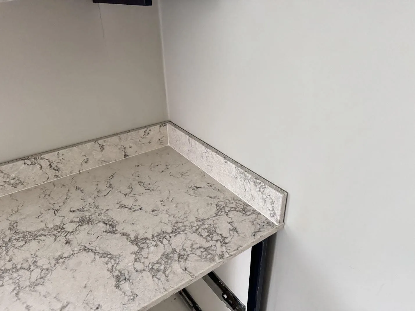 Hörn med bänkskiva och uppvikt stänkkant i polerad Caesarstone Moorland Fog, monterat i ett kök i Svedala.