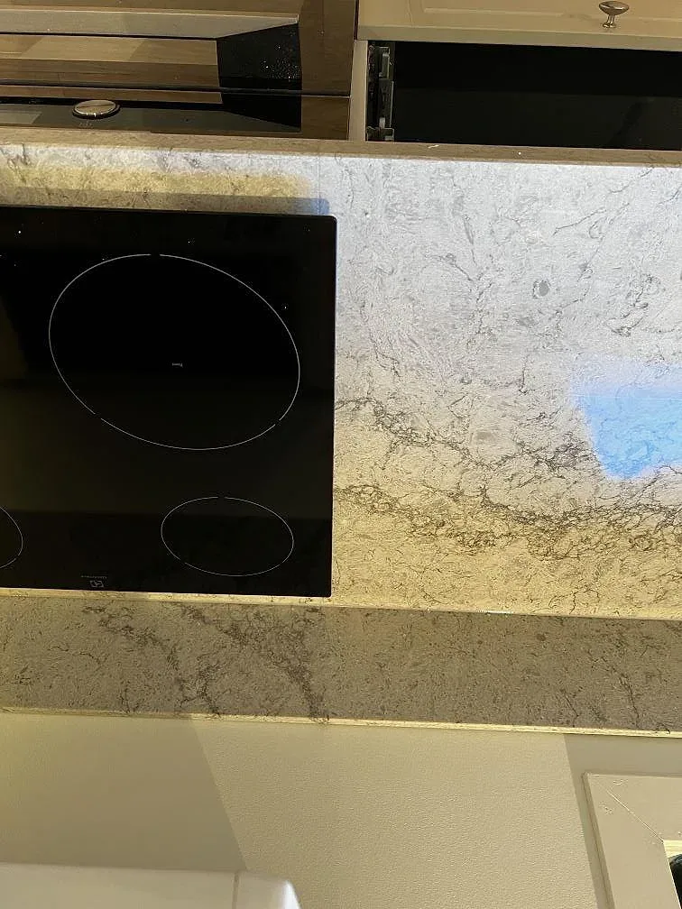 Detalj av induktionshäll infälld i köksbänkskiva i ljusgrå Caesarstone Moorland Fog i Trensum.