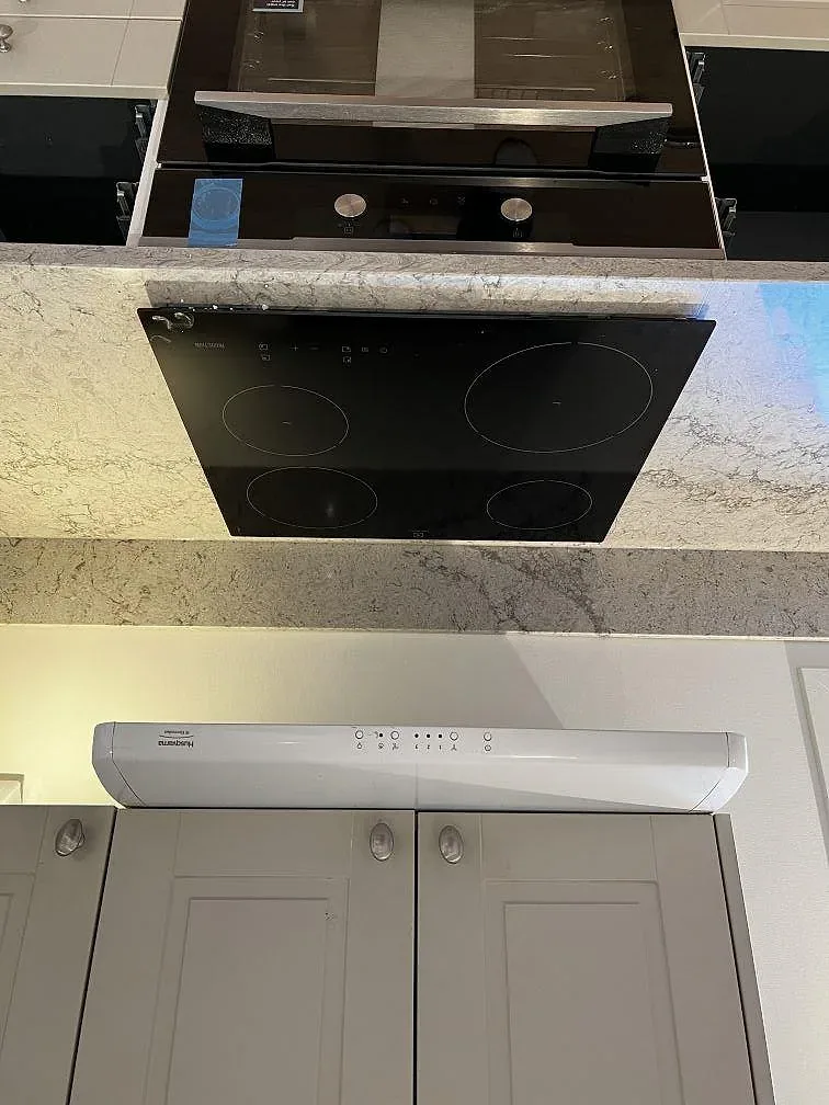 Induktionshäll och inbyggd ugn under köksbänkskiva i polerad Caesarstone Moorland Fog i ett kök i Trensum.