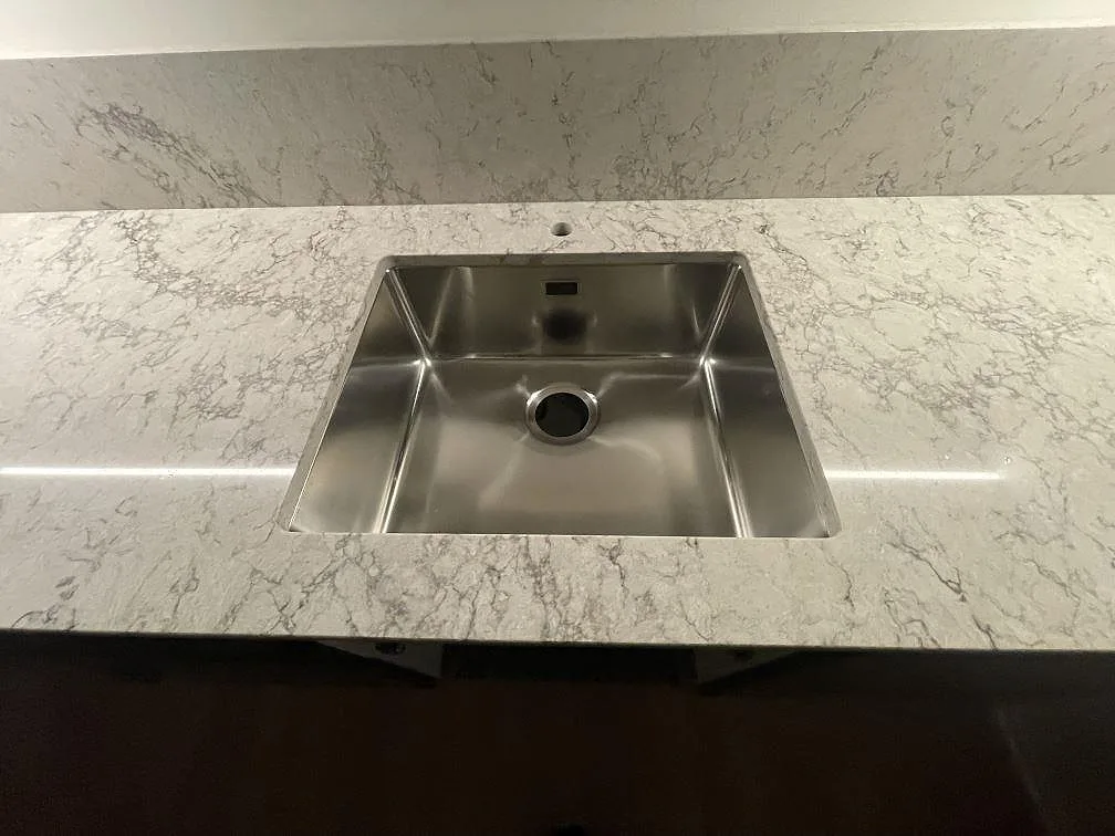 Närbild på underlimmad rostfri diskho monterad i polerad Caesarstone Moorland Fog köksbänkskiva i Tyresö.