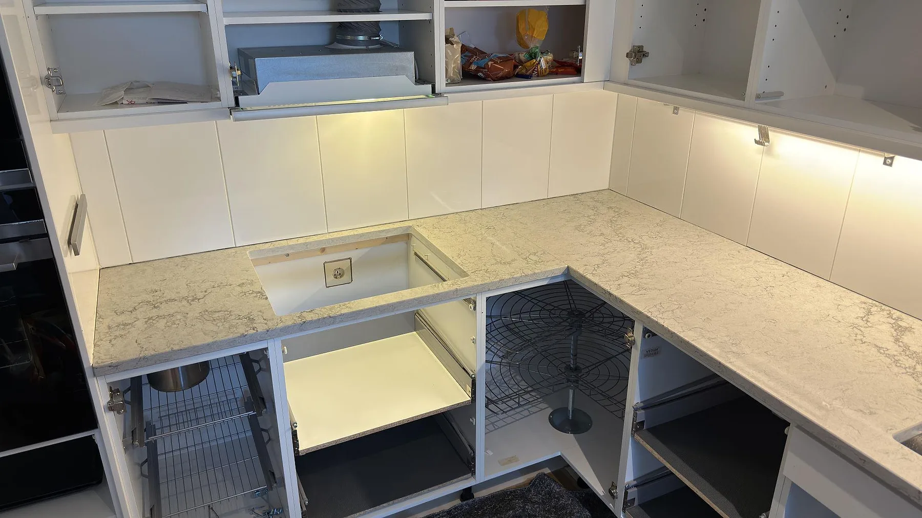 Köksbänkskiva i ljusgrå Caesarstone Moorland Fog i vinkel med förberedd urtagning och synlig ådring, fotad under montering i ett kök i Tyresöstrand.