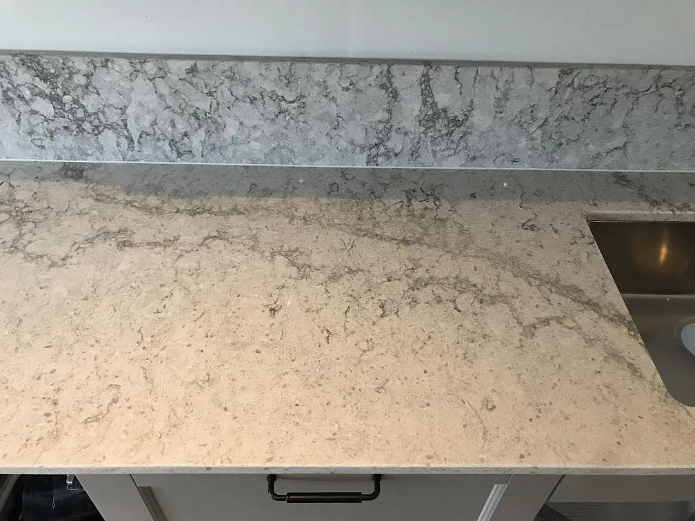 Väggbänk i Caesarstone Moorland Fog med uppvikt stänkkant i samma sten och rostfri diskho till höger i ett kök i Västra Frölunda.