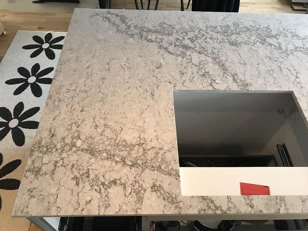 Hörn av köksö i Caesarstone Moorland Fog med urtag för häll och öppen stomme under montering i ett kök i Västra Frölunda.