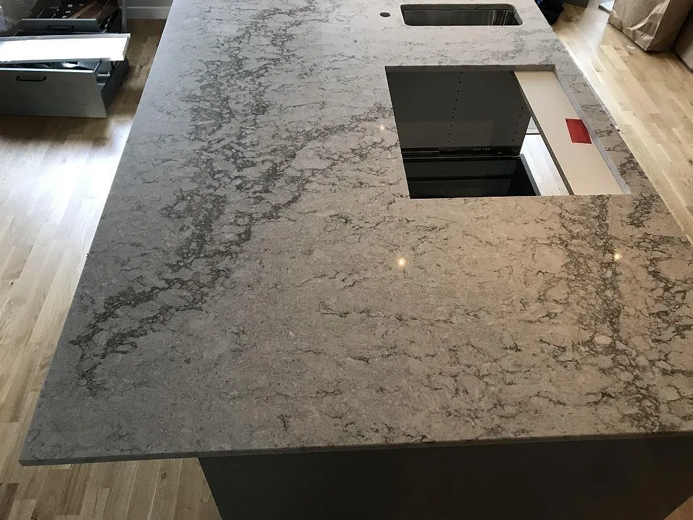 Köksö i Caesarstone Moorland Fog med urtag för häll och köksinredning under montering i ett kök i Västra Frölunda.