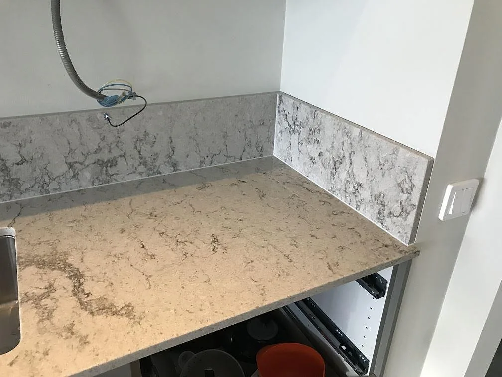 Bänkskiva i Caesarstone Moorland Fog med uppvikt stänkkant och synligt elinstallationsarbete under montering i ett kök i Västra Frölunda.