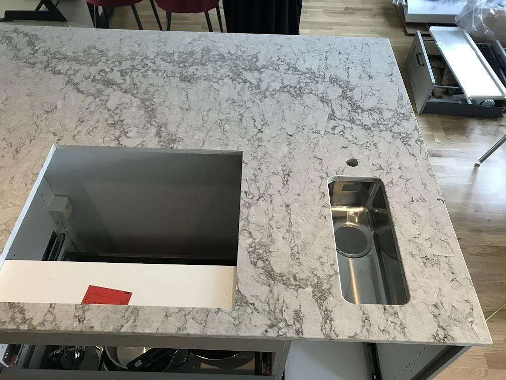 Köksbänkskiva i Caesarstone Moorland Fog sedd ovanifrån, med underlimmad rostfri diskho och urtag för häll, polerad yta, i ett kök i Västra Frölunda.