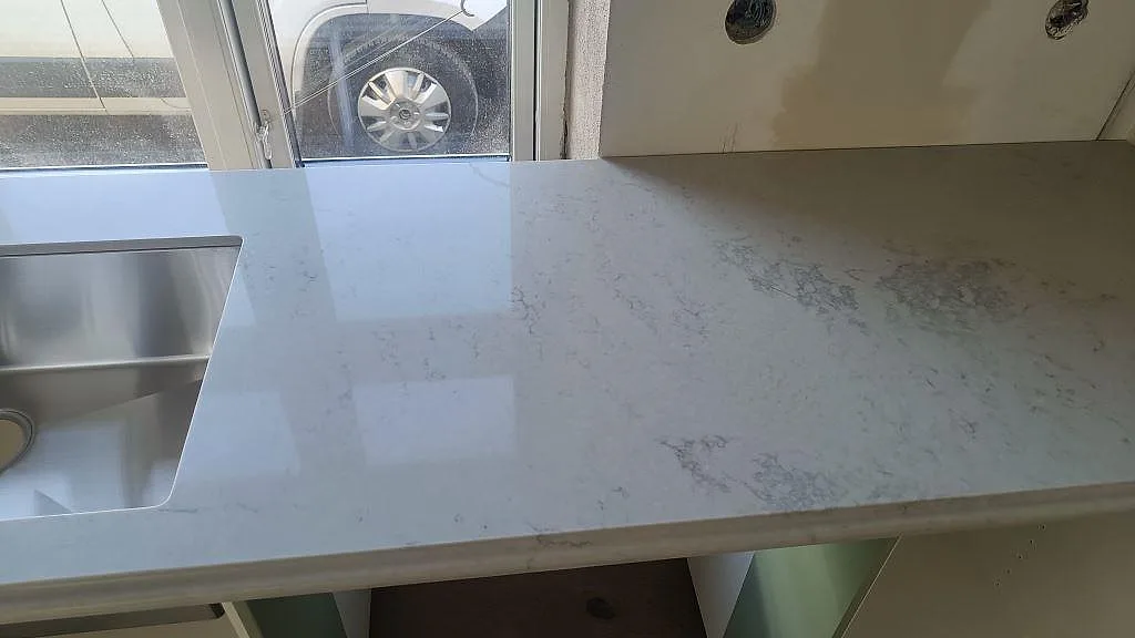 Polerad Caesarstone Noble Grey kompositbänkskiva med synlig ådring och underlimmad rostfri diskho i Ekeby.