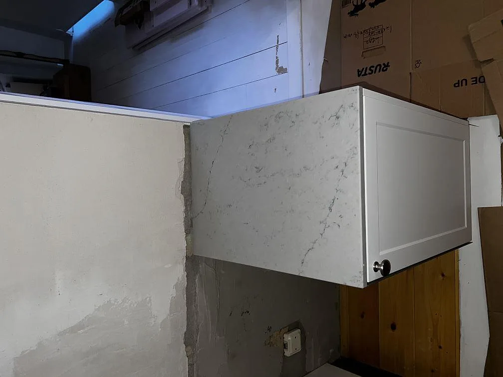 Sidovy av polerad Caesarstone Noble Grey som monterad köksbänkskiva intill ljus köksstomme i Helsingborg.